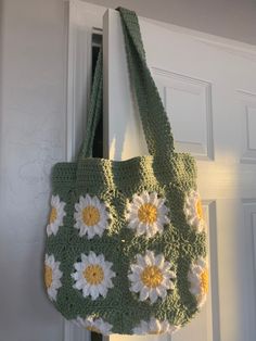 a crocheted bag hanging from the side of a door with flowers on it