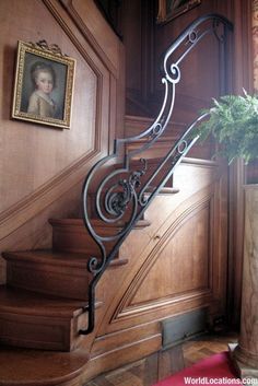 a staircase in a house with a potted plant next to it and framed pictures on the wall