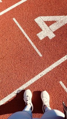 a person standing on a tennis court with their feet in the air and an arrow painted on the ground