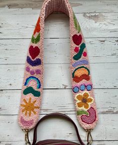 a handbag with an embroidered strap hanging from it's side on a wooden surface