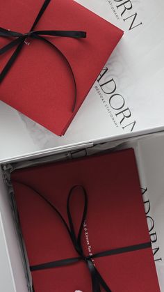 an open red gift box with a black ribbon