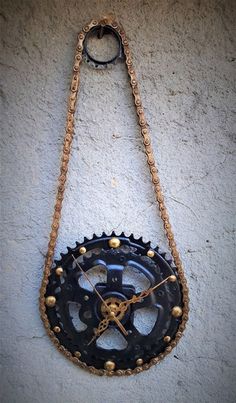 a clock made out of an old bicycle chain and gears hangs on the wall,