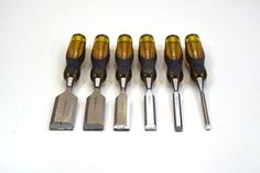 six screwdrivers are lined up in a row on a white surface with tools