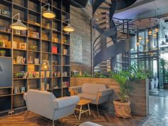 a living room filled with furniture and lots of bookshelves next to a spiral staircase