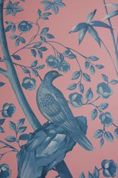 a bird sitting on top of a tree branch in front of a pink wall with blue flowers