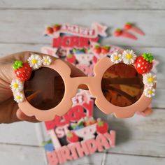 someone is holding up some sunglasses with flowers and fruit decorations on the lens rims