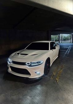 a white car is parked in a parking garage with its hood up and lights on