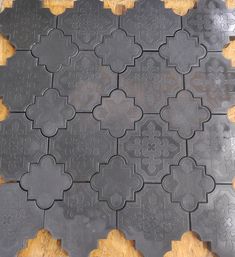 a close up of a black tile on a wooden floor with an intricate design in the middle