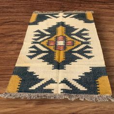 an old rug with yellow and blue designs on the side, sitting on a wooden floor