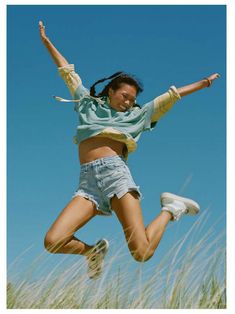 a woman jumping up in the air with her arms outstretched and legs spread wide out