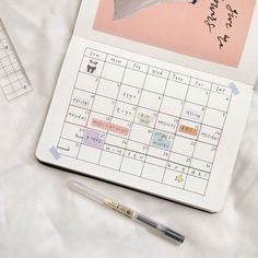 an open planner and pen sitting on top of a white sheet with the word hello kitty written on it