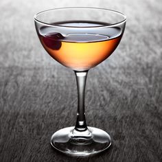 a glass filled with liquid sitting on top of a wooden table