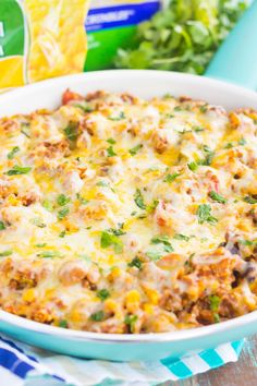 a casserole dish with meat and cheese in it on a table next to chips