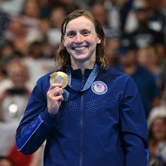 a woman holding a gold medal in front of a crowd