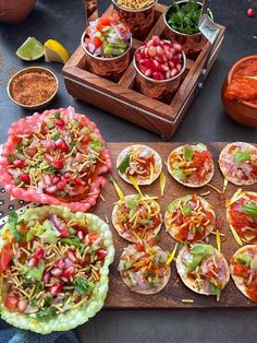 several tacos are arranged on a cutting board with bowls of salsa and condiments