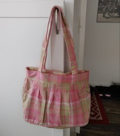 a pink and green purse hanging on a door handle in front of a white wall