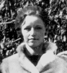 an old black and white photo of a woman wearing a fur coat in front of trees