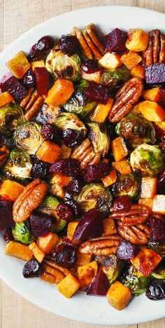 a white plate topped with brussel sprouts, carrots and pecans