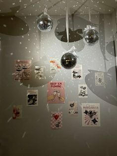 several disco balls hanging from the ceiling in front of a wall with pictures on it