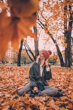 a woman sitting on the ground surrounded by leaves