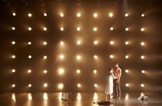 two people standing on a stage with lights behind them