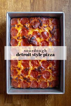 a square pepperoni pizza sitting in a pan on top of a wooden table with the words sourdough detroit style pizza