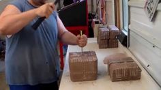 a man standing in front of a counter holding a knife and some brown boxes on top of it