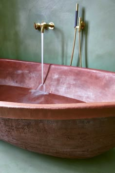 a copper bathtub with two faucets on the side and water running from it