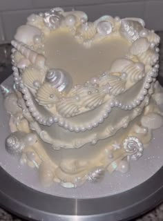 a heart shaped cake decorated with seashells and pearls