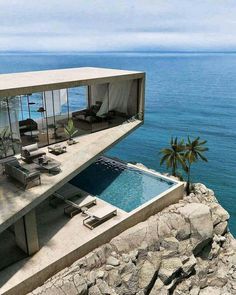 an image of a house overlooking the ocean with a pool and lounge chairs on it