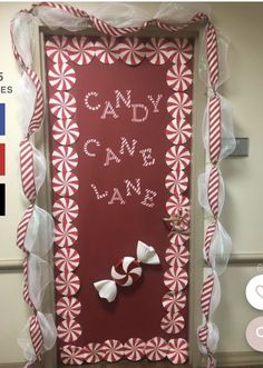 the door is decorated with red and white candy canes, ribbons, and letters