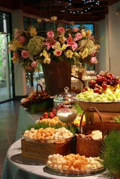 a buffet table filled with lots of different types of food and flowers in vases