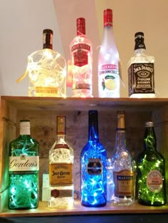 an assortment of liquor bottles on a wooden shelf with lights in the bottom and below