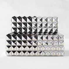 three silver boxes with black and white geometric designs on the front, one is made out of