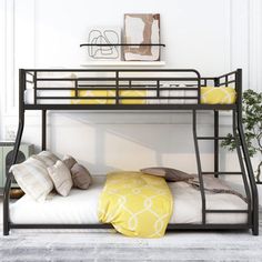 a black metal bunk bed with yellow pillows on the top and bottom, against a white wall