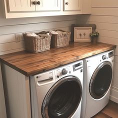 a washer and dryer in a room with wooden counter top next to white cabinets