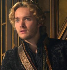 a young man wearing a crown and sitting in front of a wooden paneled wall