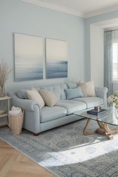 a living room filled with furniture and paintings on the wall above it's glass coffee table