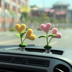 three crocheted hearts are placed on the dashboard of a car