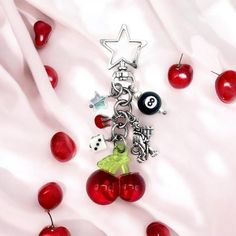 a key chain with charms attached to it on a white cloth next to cherries