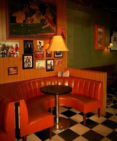 a corner booth in a restaurant with red leather seats and a black table topped with a lamp