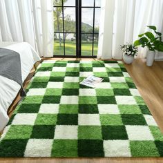 a green and white checkered rug is on the floor in front of a window