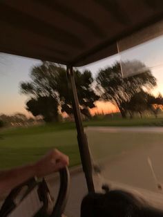 a person driving a vehicle on a road at sunset or dawn with trees in the background