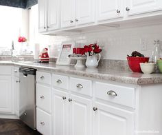 a kitchen with white cabinets and marble counter tops, including dishes on the stove top