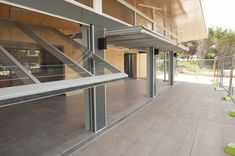 an empty building with glass walls and stairs leading up to the second floor, on a sunny day