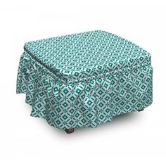 a green and white ottoman cover with an intricate pattern on it's top, sitting on