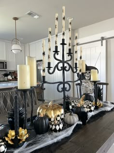 a dining room table with halloween decorations and candles on top of it, in front of a chandelier