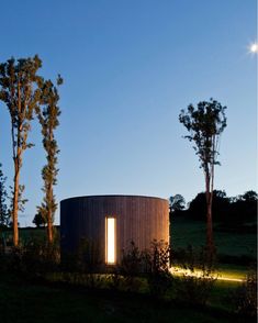 a round building sitting on top of a lush green field next to trees and bushes