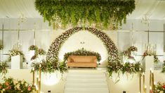 an aisle decorated with flowers and greenery at the end of a wedding ceremony venue