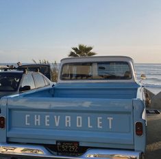 an old blue chevrolet truck parked on the beach